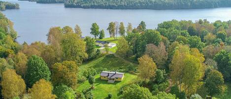 A lakeside property with a house surrounded by lush greenery and a view of the lake.