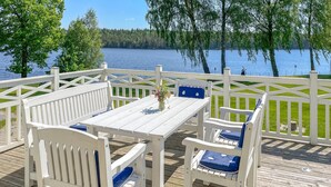 A deck with white furniture and a view of a lake.