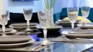 A dining table set with plates, cutlery, and a vase with yellow flowers.