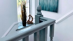 A staircase with a balustrade, a potted plant, and a painting on the wall.