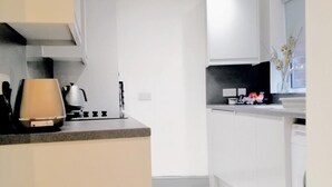 A modern kitchen with white cabinets, a gas stove, and recessed ceiling lights.