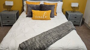 Un dormitorio con cama, dos mesitas de noche y una obra de arte colgada en la pared.