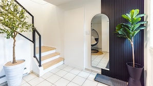 Un escalier avec des marches recouvertes de bois, un sol carrelé de blanc et deux plantes en pot.