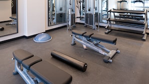A gym with exercise equipment including benches, a rowing machine, and a treadmill.