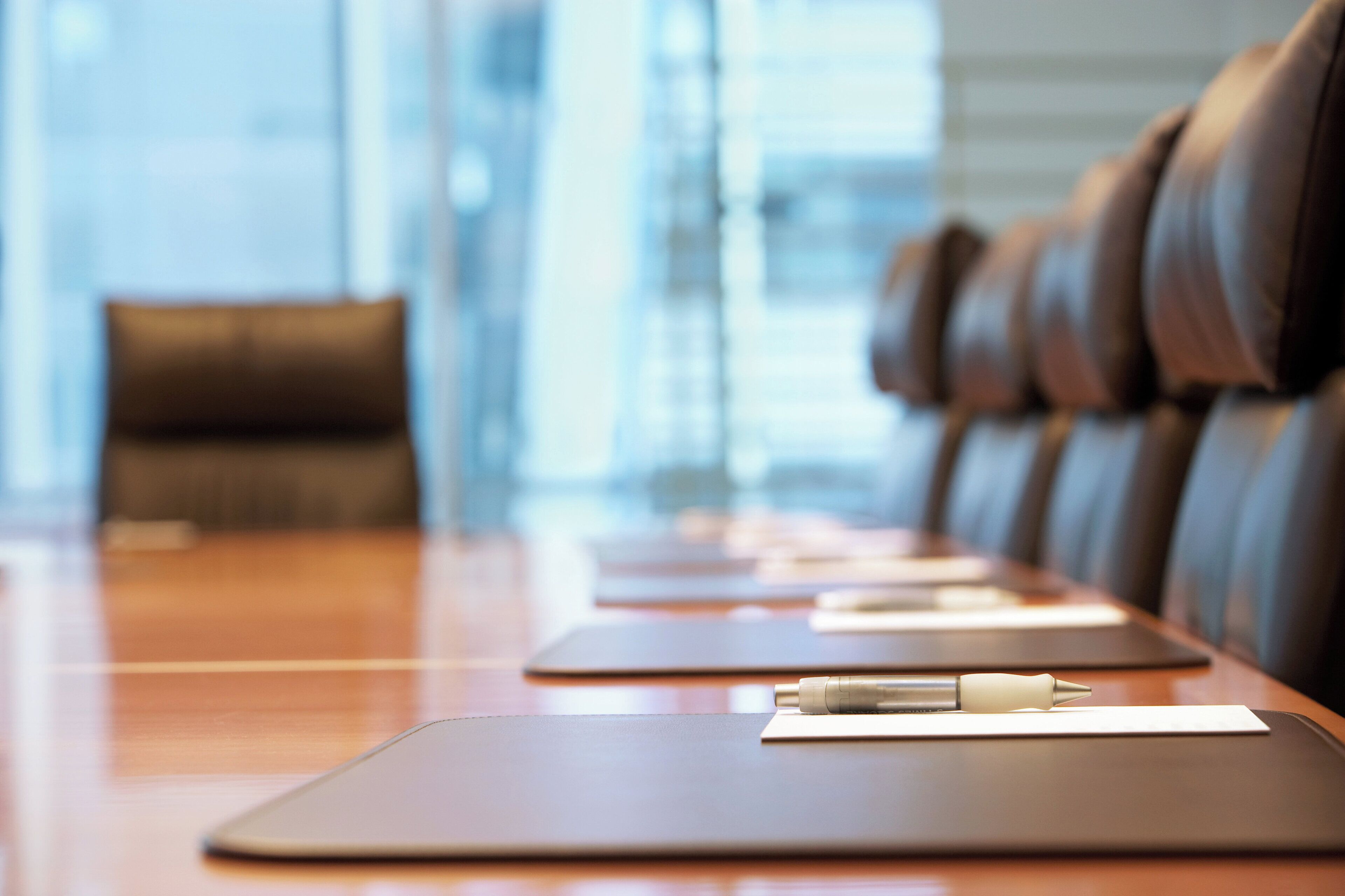 A conference table with leather chairs, a pen, and a notepad.