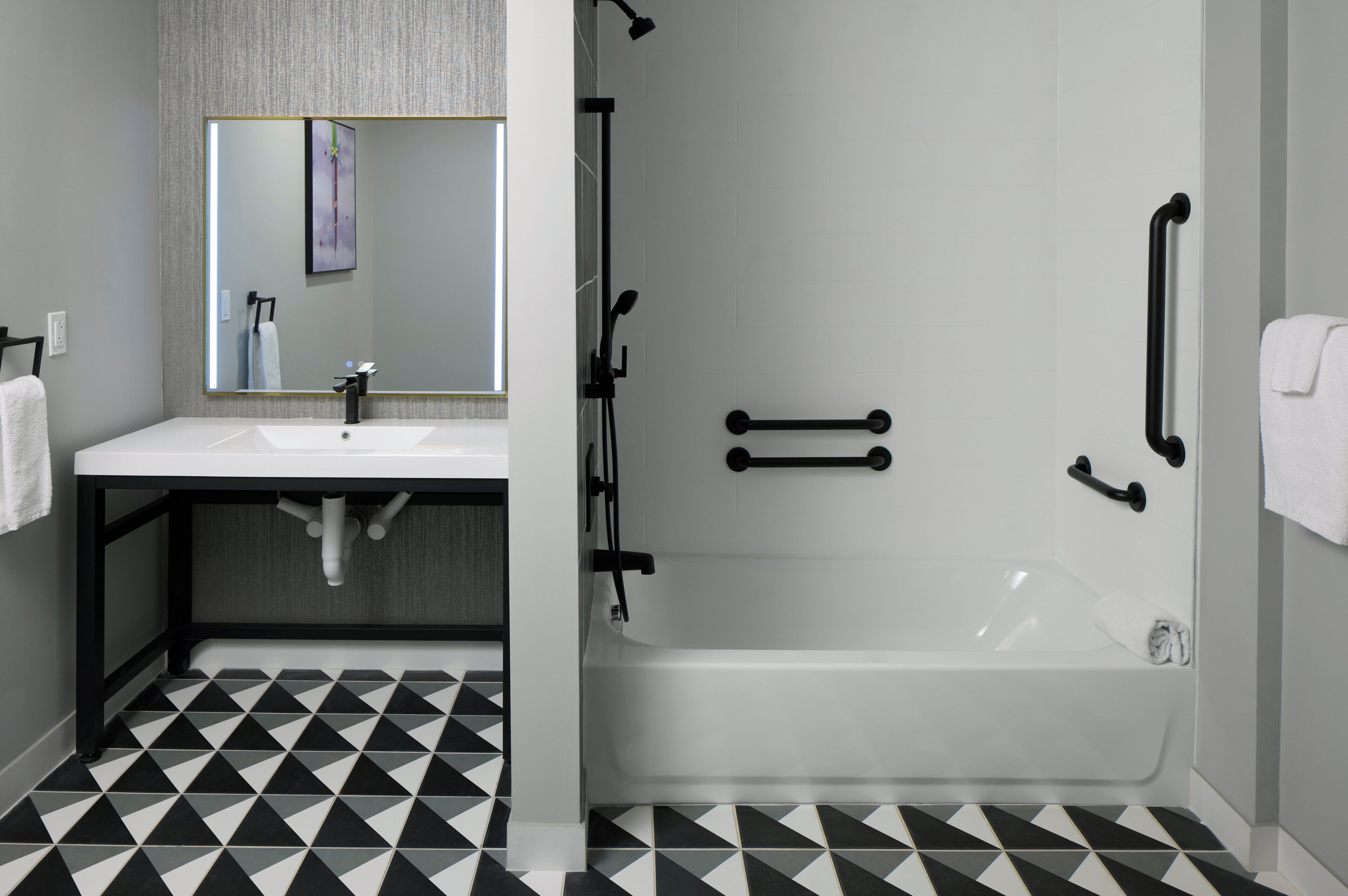 A bathroom with a white sink, mirror, and black and white patterned floor tiles.