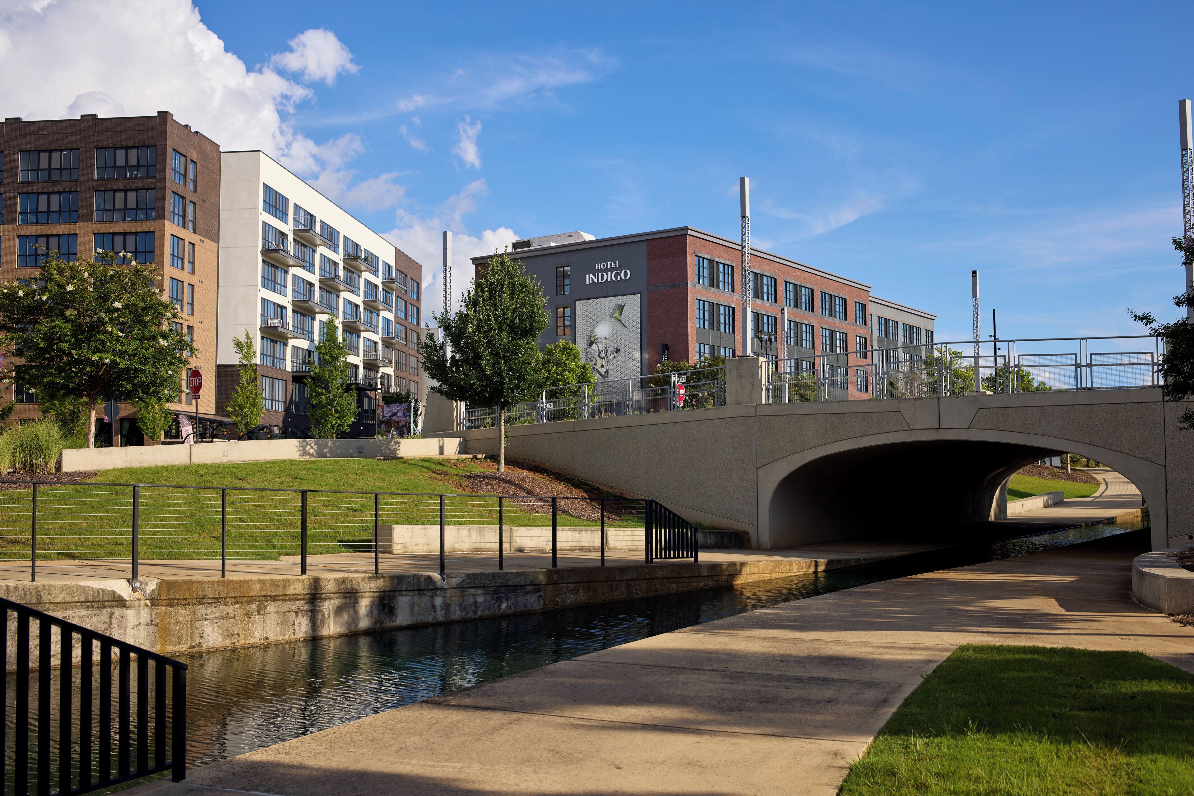 A bridge over a canal with a hotel named 'Hotel Indigo' in the background.