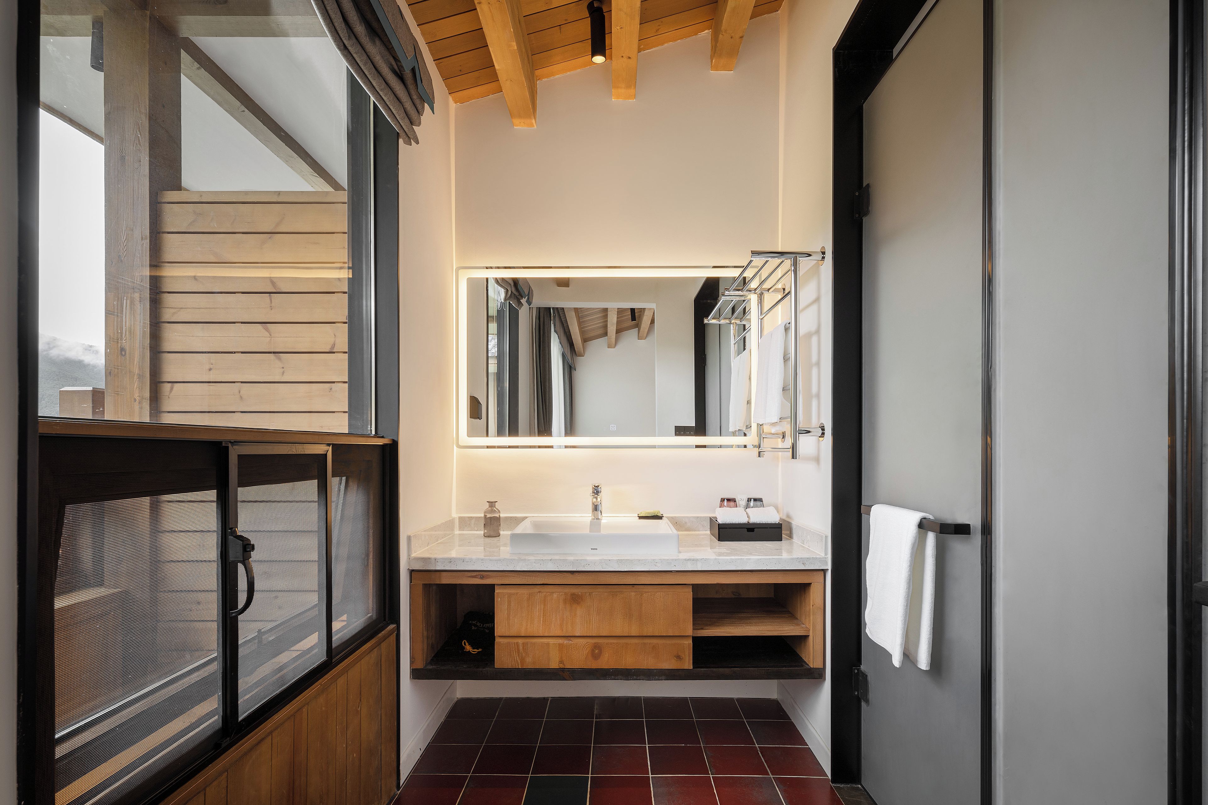 A modern bathroom with a large mirror, a double sink, and a wooden vanity.