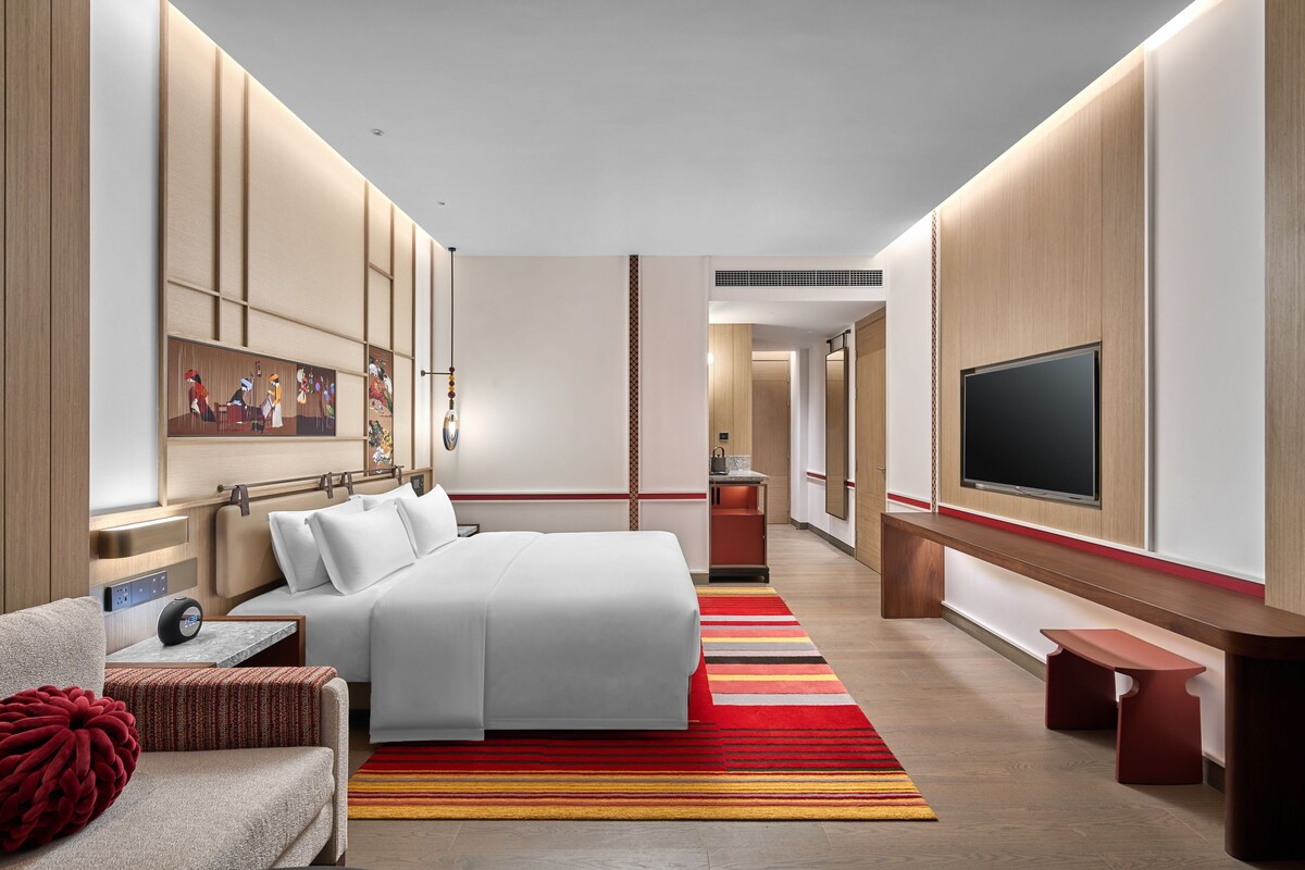 Une chambre d’hôtel moderne dotée d’un grand lit, d’une télévision à écran plat, d’un bureau et d’un coin salon.