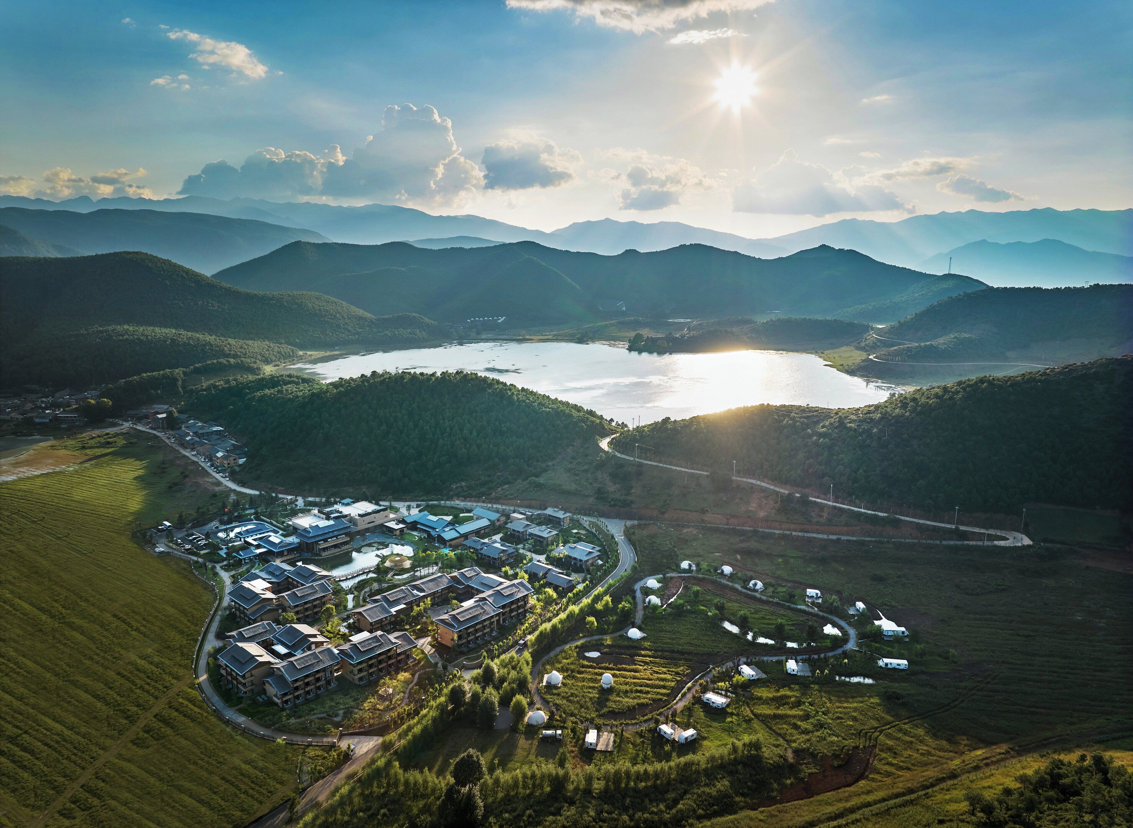 An aerial view of a resort with multiple buildings, a lake, and surrounding mountains.