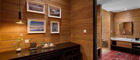 A wooden-paneled bathroom with a vanity, framed pictures, and a red-tiled floor.