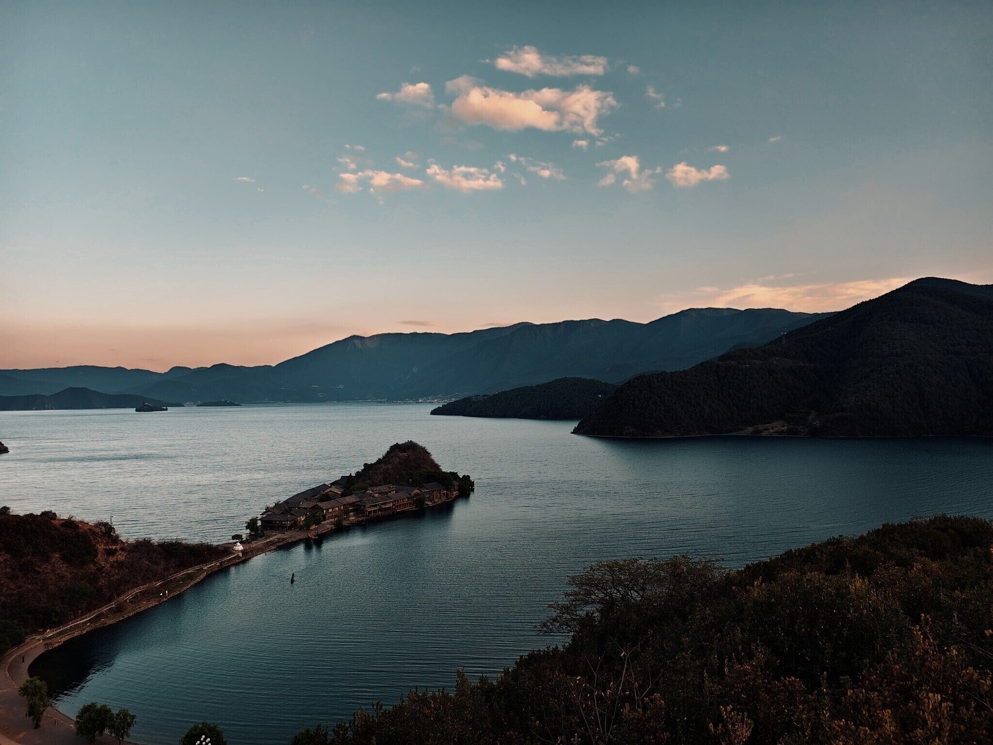 A coastal landscape with a small island and a bridge leading to it.