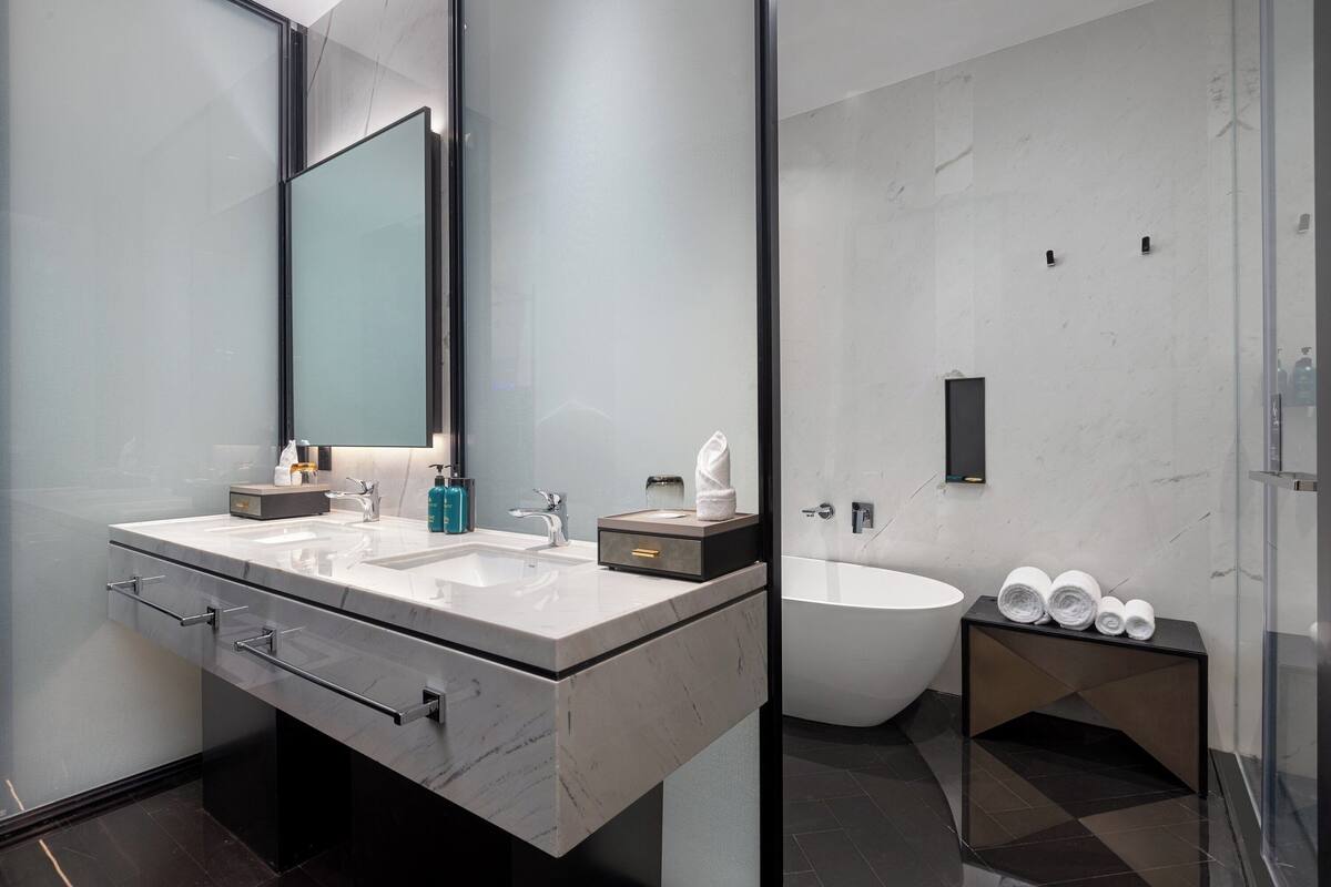 A modern bathroom with a large bathtub, two sinks, and a glass shower enclosure.