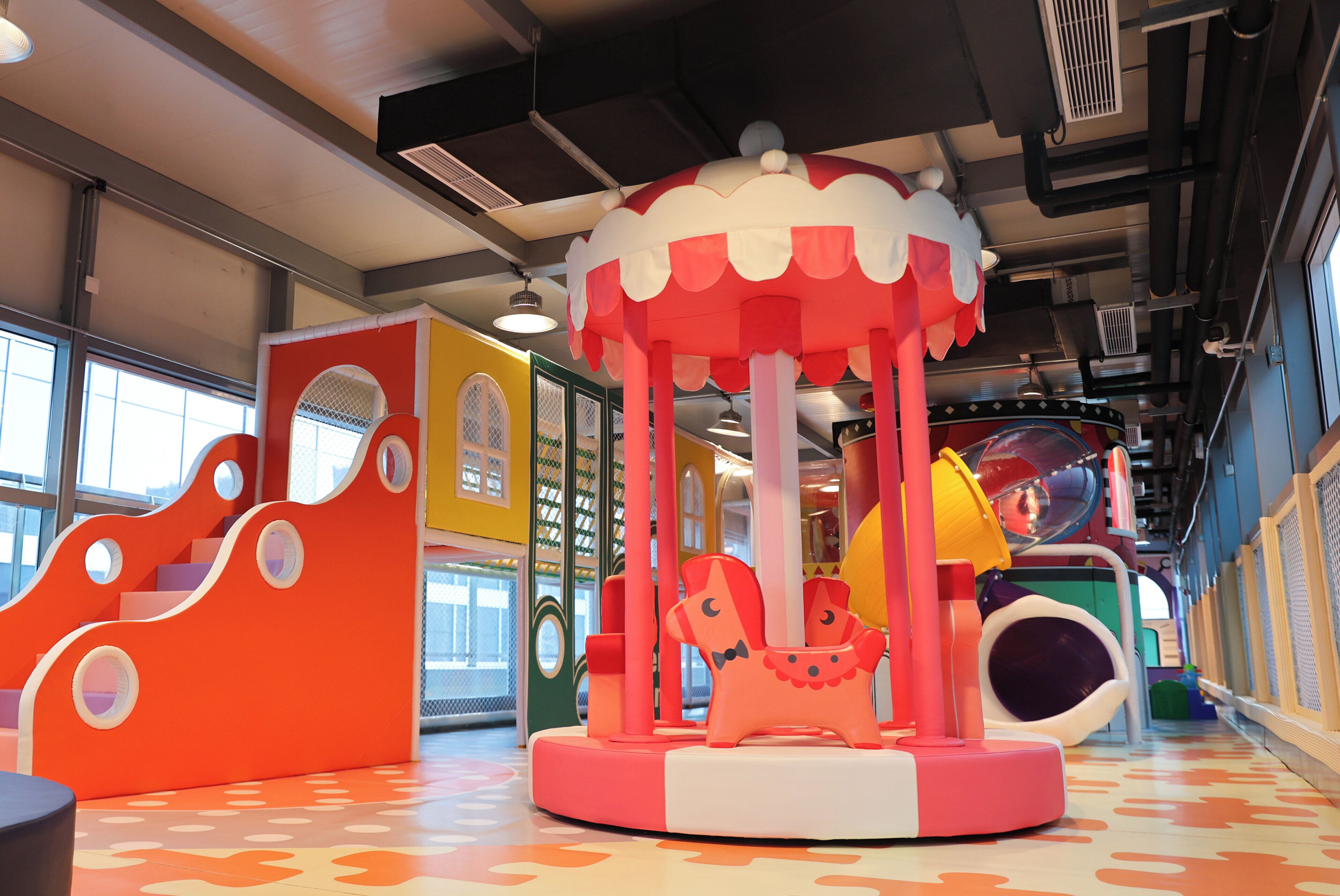 Un espace de jeux pour enfants avec un carrousel, des toboggans et des structures colorées.