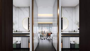 A modern bathroom with two sinks, marble walls, and a city view.