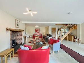A spacious living area with a fireplace, red and grey sofas, a checkered rug, and a staircase leading to another level.