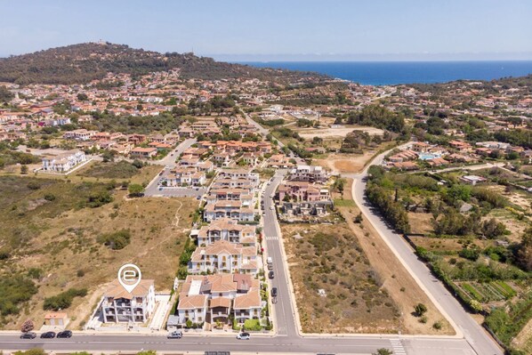 An aerial view of a residential area with houses, roads, and a hill in the background.