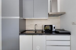 A modern kitchen with grey cabinets, a stainless steel sink, and a microwave. - Lemon Apartment 1 - Dreaming Vacation (Tortolì)