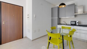 Una cocina moderna con armarios grises, un microondas y una mesa de comedor de vidrio con sillas amarillas.