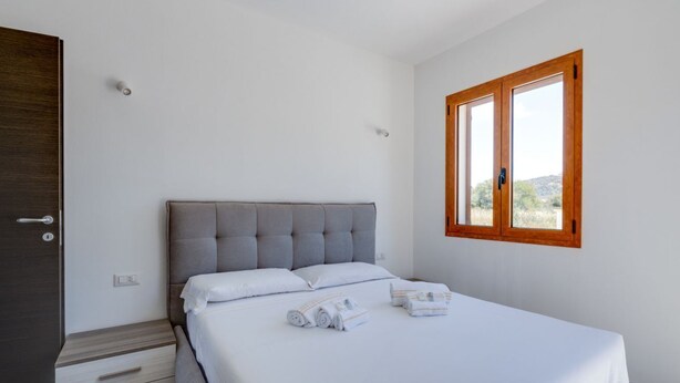 Un dormitorio con una cama, un armario de madera y una ventana con vistas.