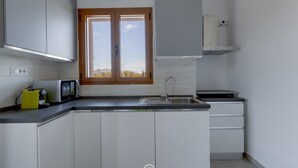A modern kitchen with white cabinets, a built-in microwave, a sink, and a window with a view. - Orange Apartment 4 - Wonderful Vacation (Tortolì)