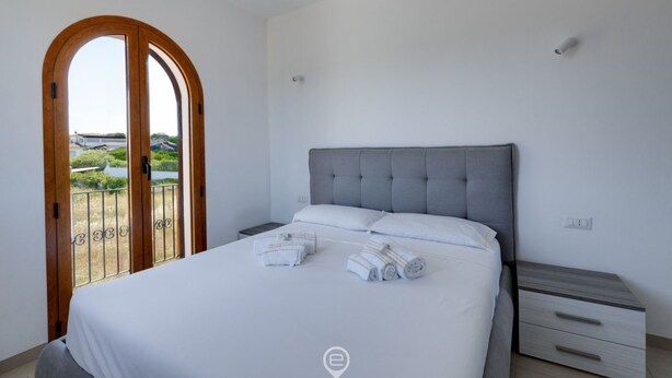 A bedroom with a bed, a nightstand, and a view of a bridge and greenery. - Orange Apartment 4 - Wonderful Vacation (Tortolì)