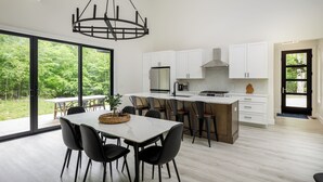 Una cocina moderna con una isla grande, armarios blancos y un comedor con mesa y sillas.