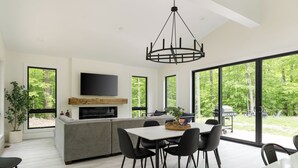 Una cocina moderna con isla integrada, zona de comedor con sillas y ventanas amplias que ofrecen vistas al exterior.