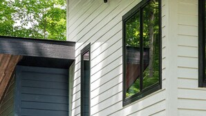 Una casa moderna de dos pisos con puerta principal negra, un letrero de bienvenida y el número 545 en la puerta.