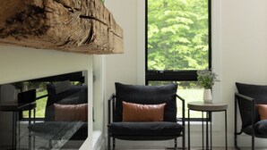 Una sala de estar moderna con una viga de madera grande, un sofá y vistas a la vegetación a través de un ventanal.
