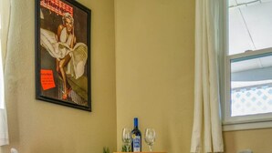 A corner room with a table and two chairs, a poster on the wall, a window with curtains, and a plant. - Retro Retreat - A Desert Oasis (Twentynine Palms)