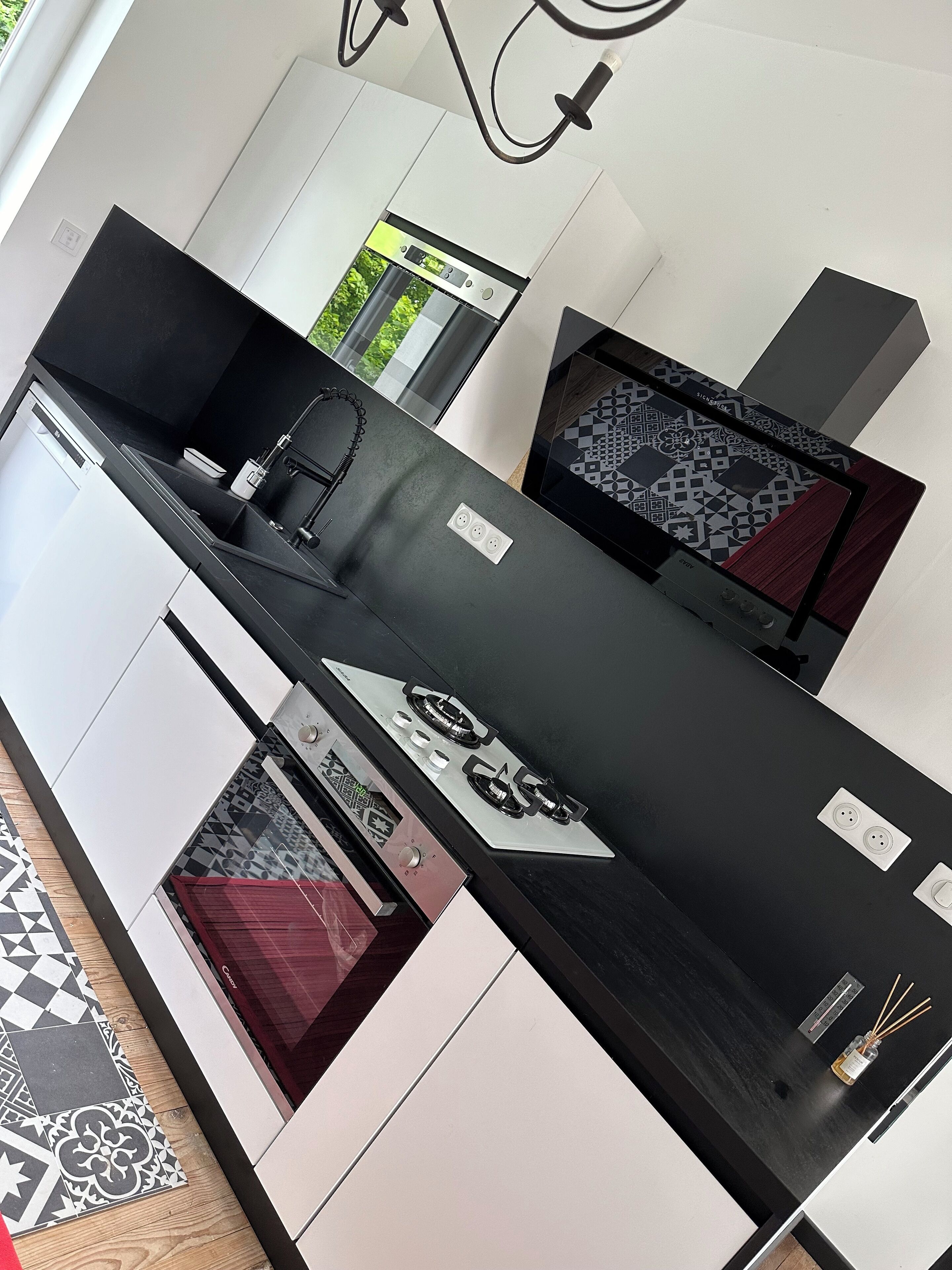 A modern kitchen with a black countertop, stainless steel appliances, and a patterned backsplash.
