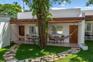 A modern building with a covered patio area, hammocks, and a stone pathway. - Charm Suites Masters (Arraial d' Ajuda)