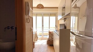 Een moderne keuken met een koelkast, een telefoon en een raam met uitzicht op een balkon.