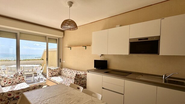 A compact kitchen with a built-in microwave, a sink, and a dining area with a table and chairs. -  SE085 - new two-room apartment facing the sea at the ''Pyramids'' (Senigallia)