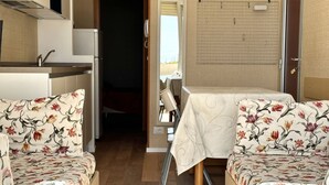 A compact RV interior with a kitchenette, two sofas with floral upholstery, a dining table, and a shower area. -  SE085 - new two-room apartment facing the sea at the ''Pyramids'' (Senigallia)