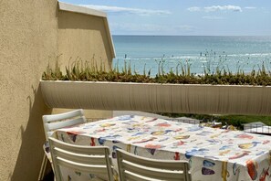 Un balcon avec une table et des chaises, donnant sur la mer.