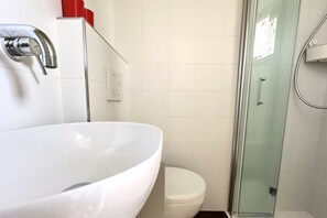 Un baño con lavamanos blanco, inodoro y cabina de ducha de cristal.