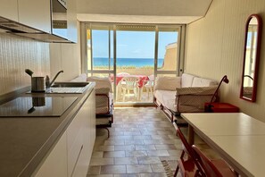 Una cucina compatta con vista sul mare, un'area pranzo con tavolo e sedie, e un grande specchio.