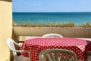 Un balcón con mesa y sillas, con vista a una masa de agua.