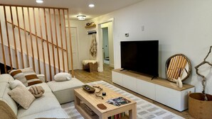 Ein modernes Wohnzimmer mit Sofa, Couchtisch, Fernseher und Holzeinrichtung.