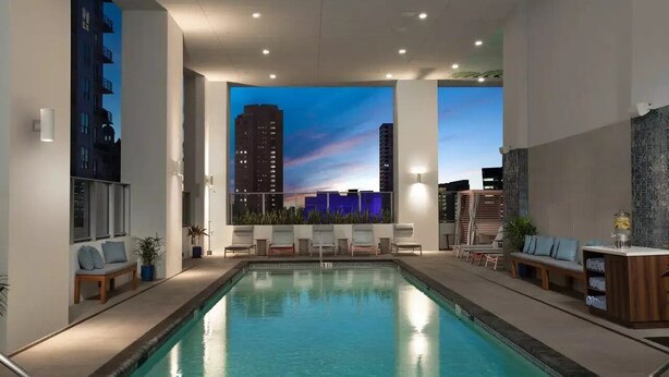 A modern indoor pool area with a cityscape mural on the walls, lounge chairs, and a bar area. - Apartment Downtown Miami (Miami)
