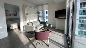 A modern living room with a sofa, a chair, a TV, and a large window. - Apartment Downtown Miami (Miami)