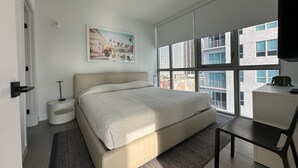 A modern bedroom with a large bed, a desk, and a window with a city view. - Apartment Downtown Miami (Miami)