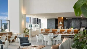 A modern rooftop bar with white furniture, a bar counter, and a city view. - Apartment Downtown Miami (Miami)