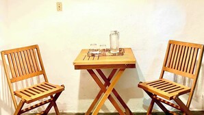 A small room with two wooden chairs, a table, and a hanging lamp. There are three paintings on the wall. - Room #4 two blocks from the Malecon (La Paz)