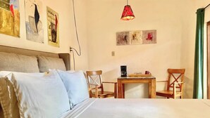 A bedroom with a bed, two chairs, a small table, a coffee maker, and artwork on the walls. - Room #4 two blocks from the Malecon (La Paz)