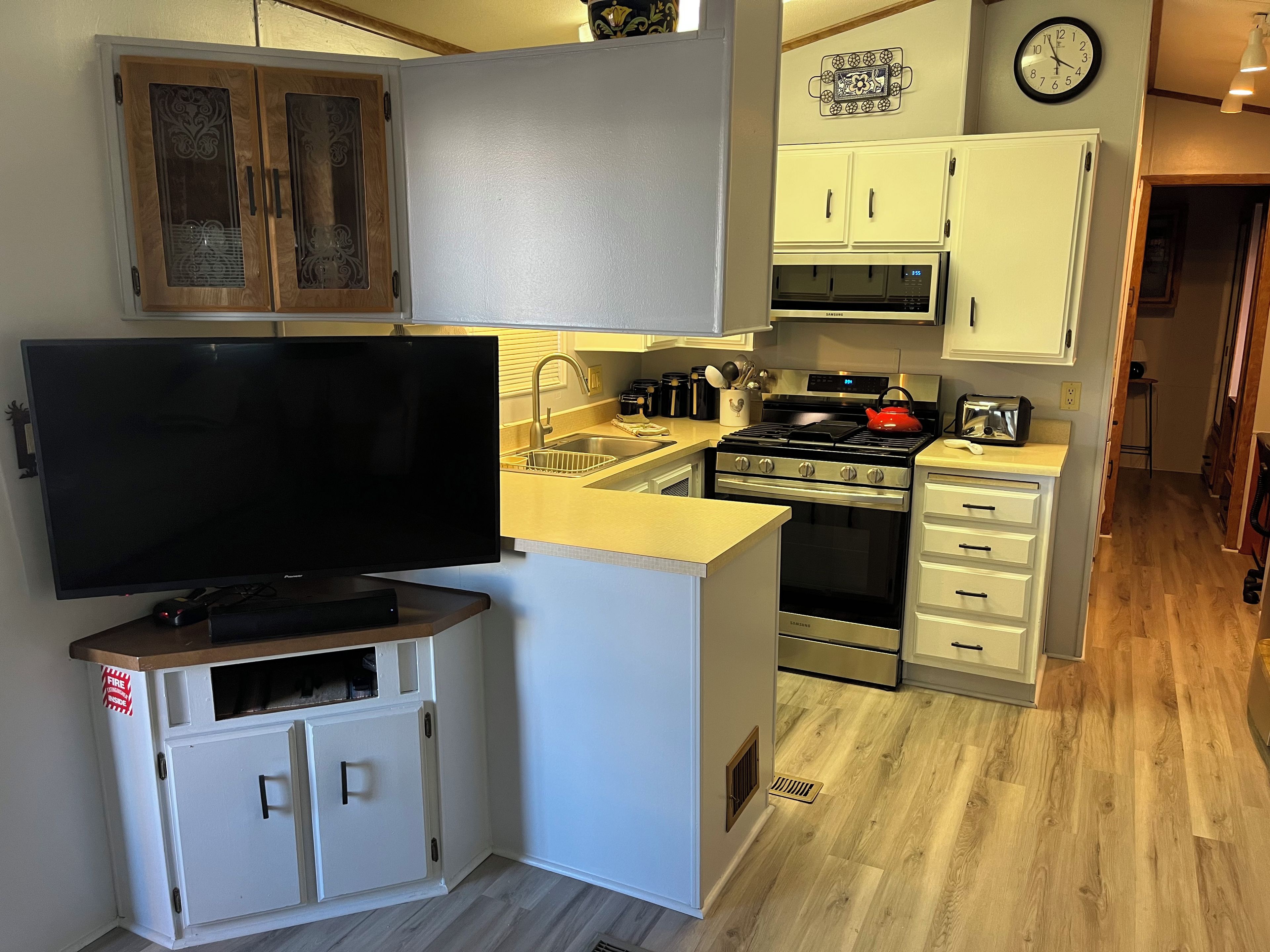 A compact kitchen with a TV, microwave, stove, and cabinets.