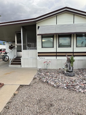 A single-story building with a covered porch, a motorcycle parked outside, and a cactus sculpture in the front yard. - Voyager RV Resort & Hotel Vacation Rental Walk to the beautiful Sonoran Desert! (Tucson)