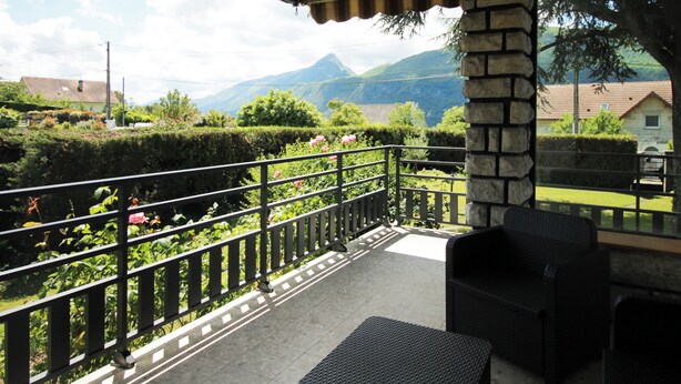 Un balcon avec vue sur les montagnes, un pilier en pierre et un plafond en bois.
